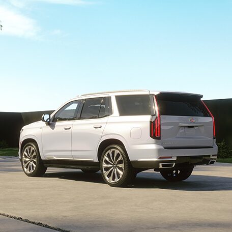 Three Quarters Rear View of a White Cadillac SUV under a Sunny Sky