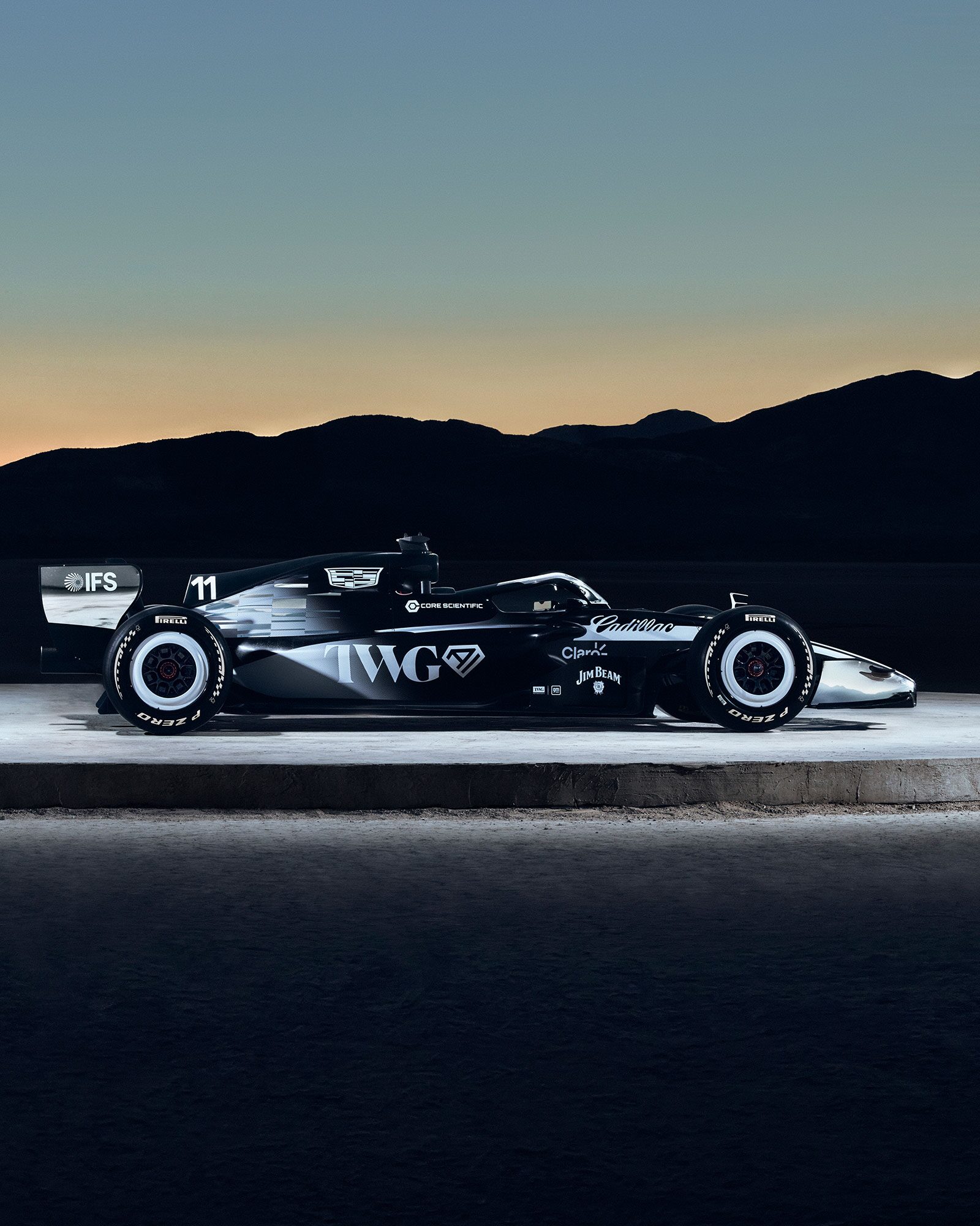 Two Cadillac Racing Cars Facing Outwards on a Circular Structure Outside in the Evening.