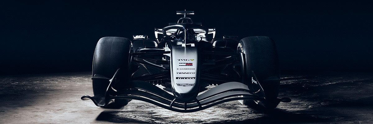 A Low Front View Of A Cadillac-Branded Formula Race Car Illuminated Dramatically Against a Dark Desert Landscape.