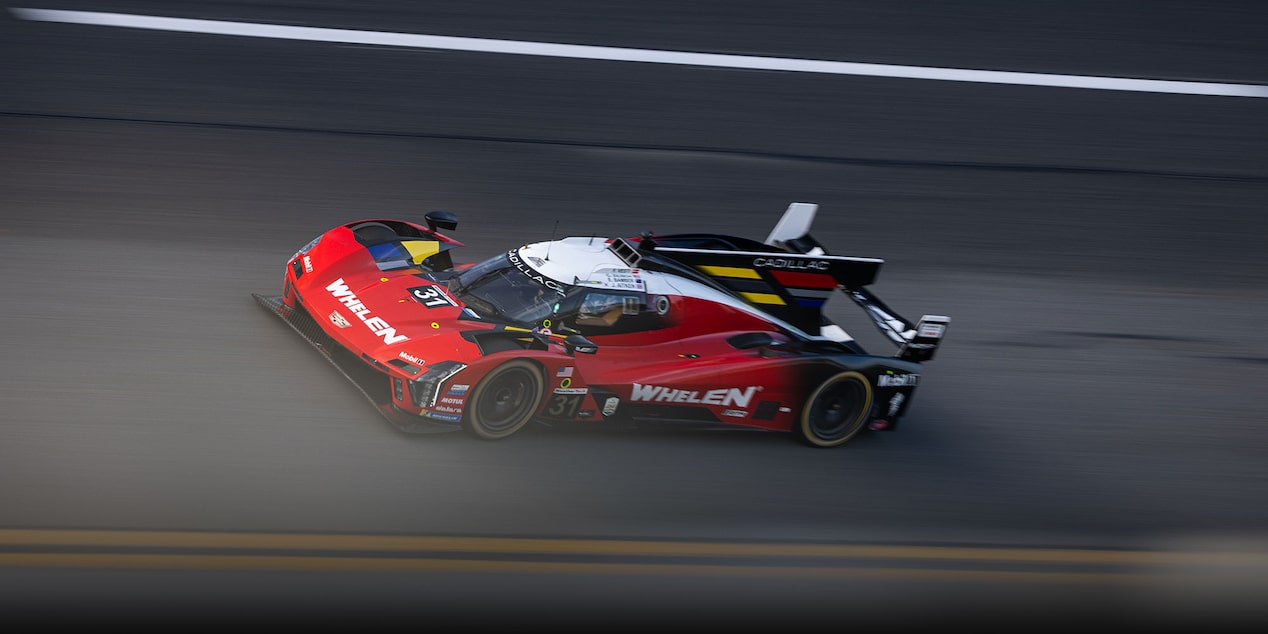 A Red and White Cadillac V-Series.R Race Car With Number 31 Speeding on a Dark Asphalt Track.