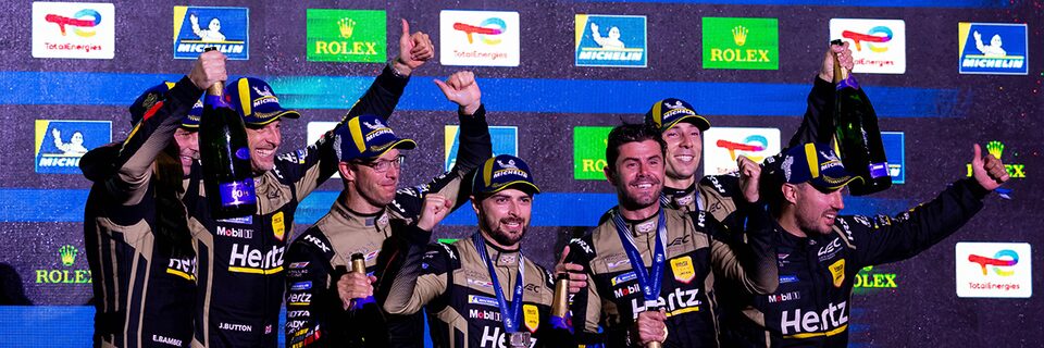 The Cadillac Race Team Celebrating a WEC Win by Smiling, Holding up Thumbs Up, and Champage