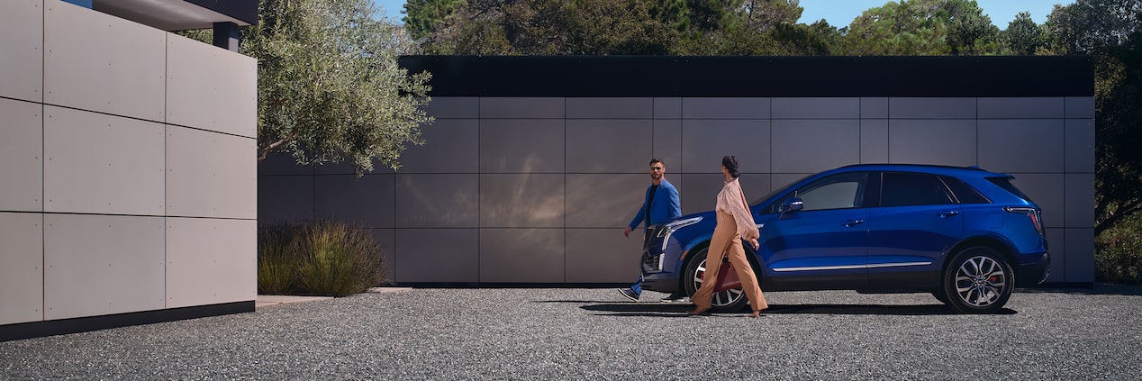 A Couple Walks Away from Their Parked XT5 As They Approach Their Luxurious Home