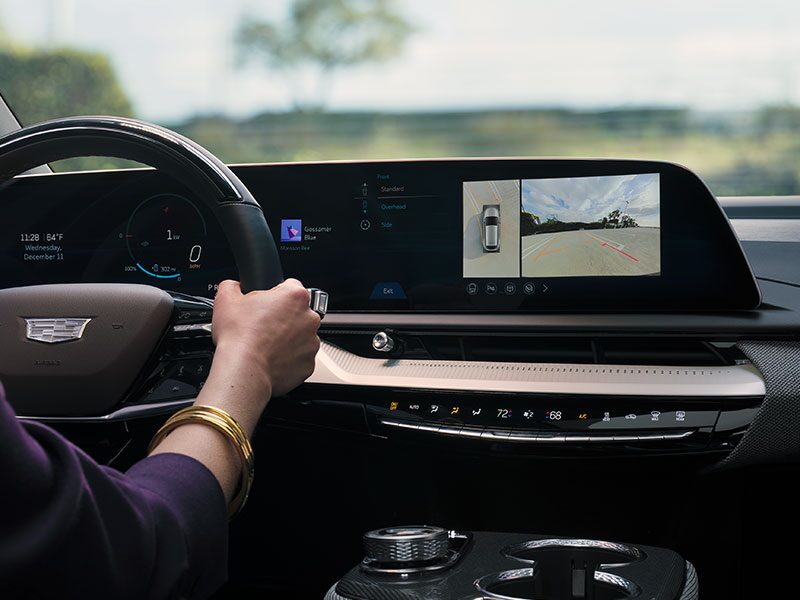 Passenger Seat View of a Driver Checking Her Safety Features in a Cadillac while Driving