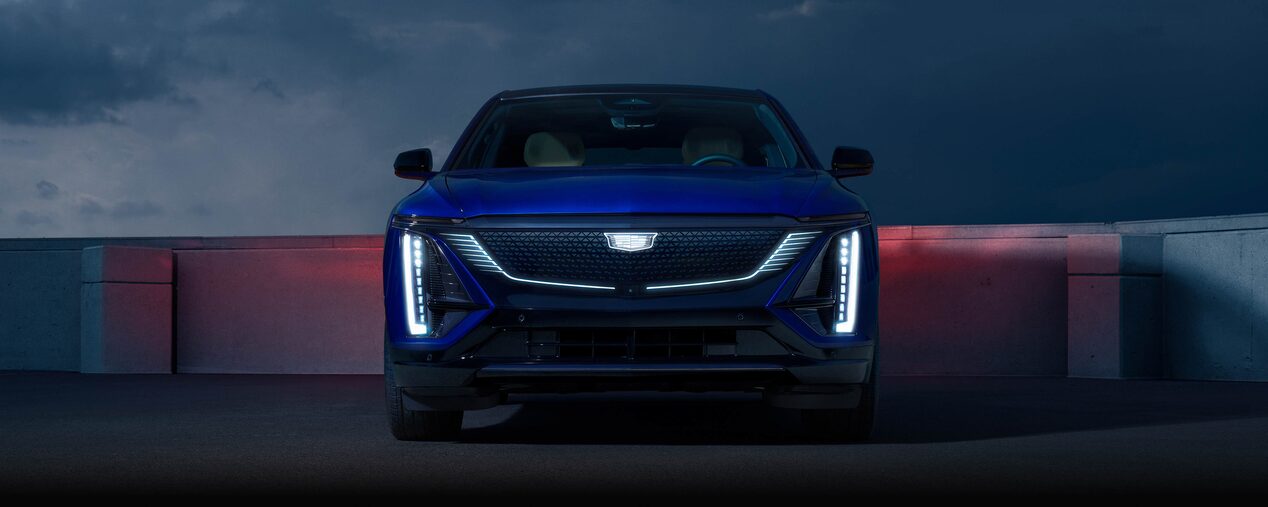 The Blue Cadillac LYRIQ All-electric SUV Parked at Night with the Headlights On