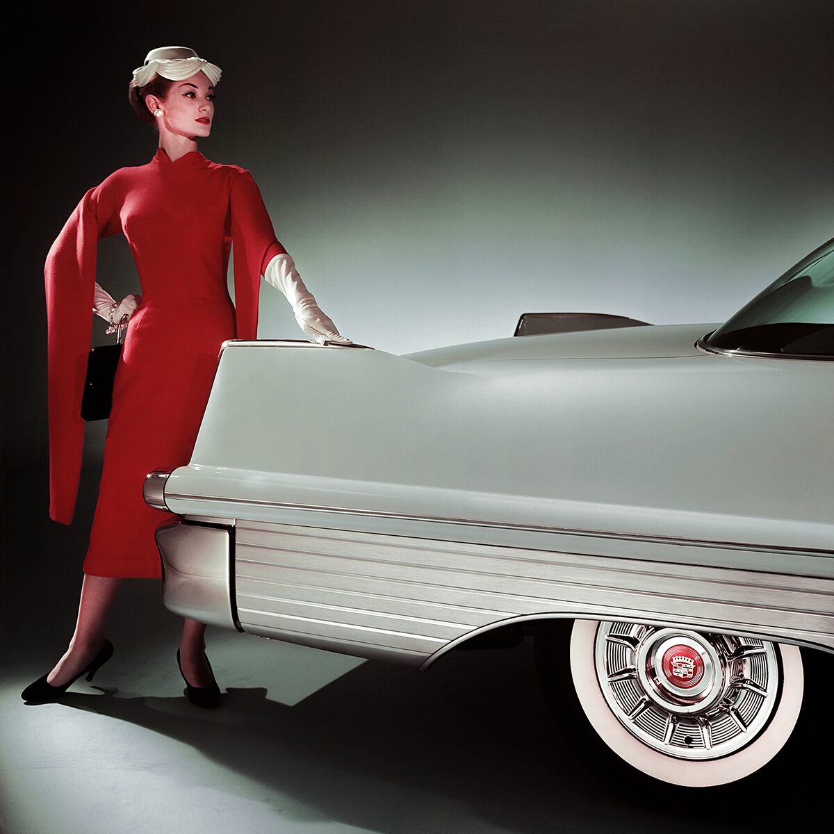 A Fashionably Dressed Woman Leaning on the Rear End of a Classic White Cadillac