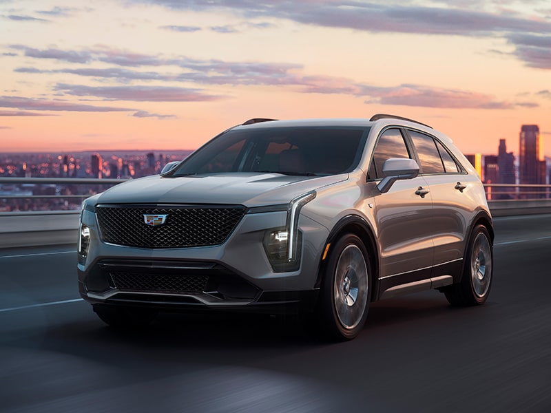 The 2025 Cadillac XT4 Driving on an Overpass with the City in the Distance During a Sunset