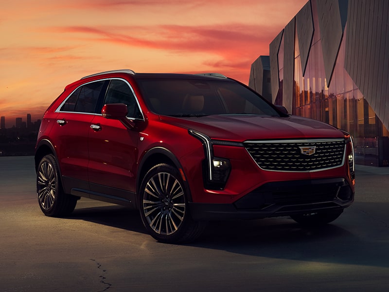 A Red 2025 Cadillac XT4 Parked Near an Industrial Building During a Beautiful Sunset