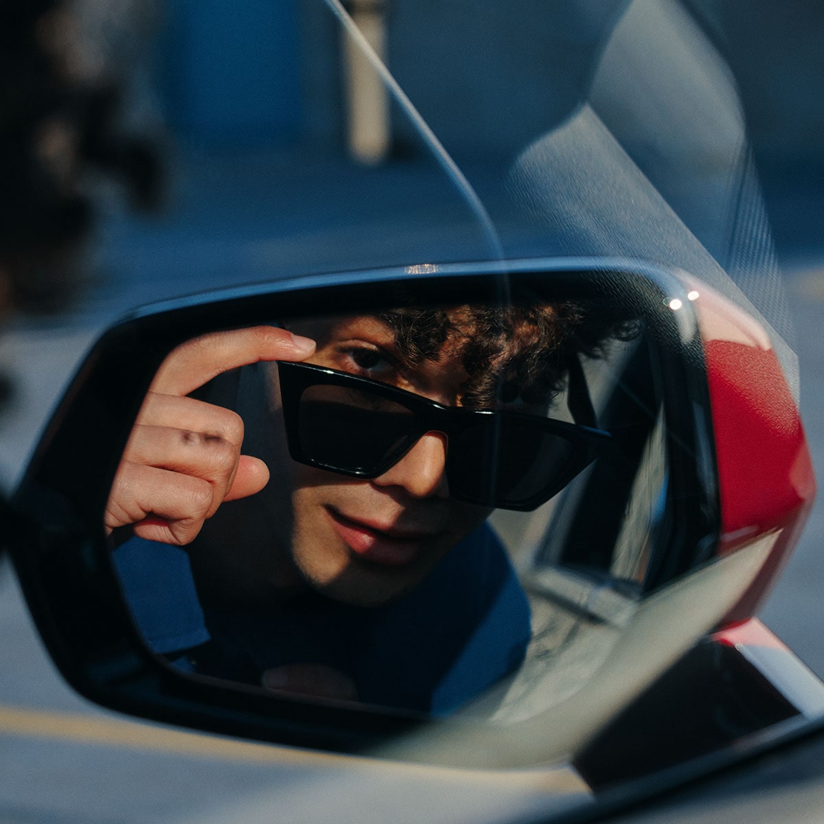 A Man Lowering Sunglasses and Looking into a 2025 Cadillac XT4 Side Mirror