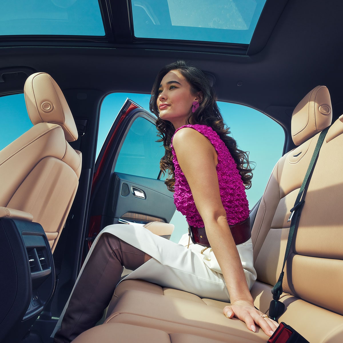 A Woman Enjoys a Breeze in the Backseat of a 2025 Cadillac XT4 on a Clear Day