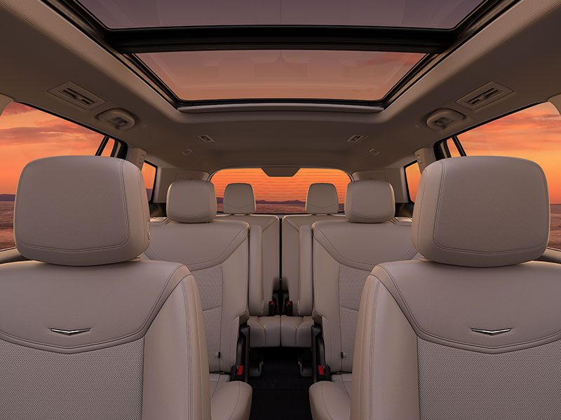 Three Rows of Tan Leather Seats Inside the New Cadillac XT6 Parked Under the Sunset
