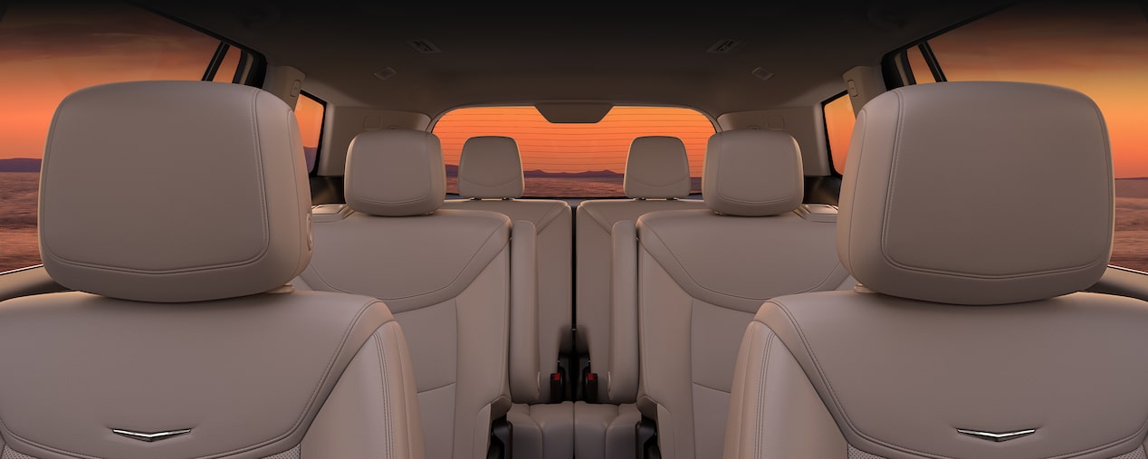 Three Rows of Tan Leather Seats Inside the New Cadillac XT6 Parked Under the Sunset