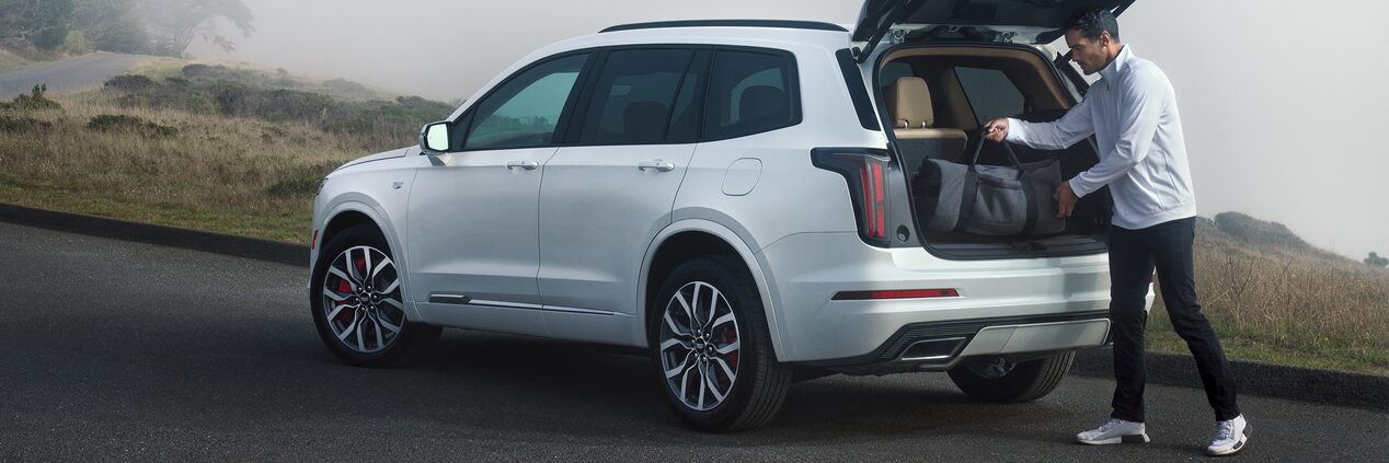 A Man Unloads Cargo from the Trunk of His Cadillac XT6 with Thick Fog in the Distance