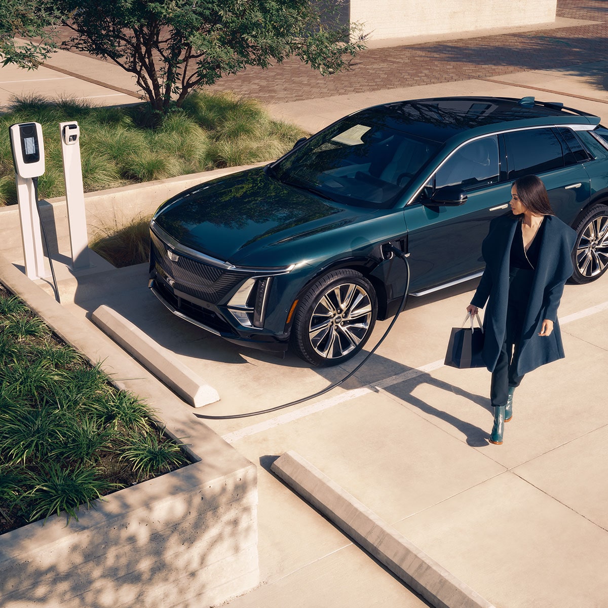 A Business Women Walking Away From a 2025 Cadillac LYRIQ Charging at a Public Charger