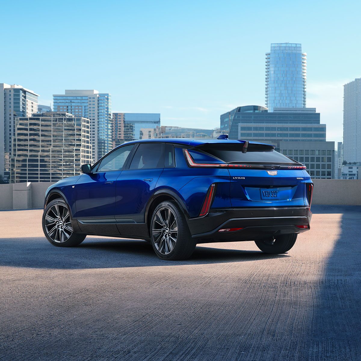 Three-Quarter Rear View of a Blue 2025 Cadillac LYRIQ Parked Overlooking the City Skyscrapers