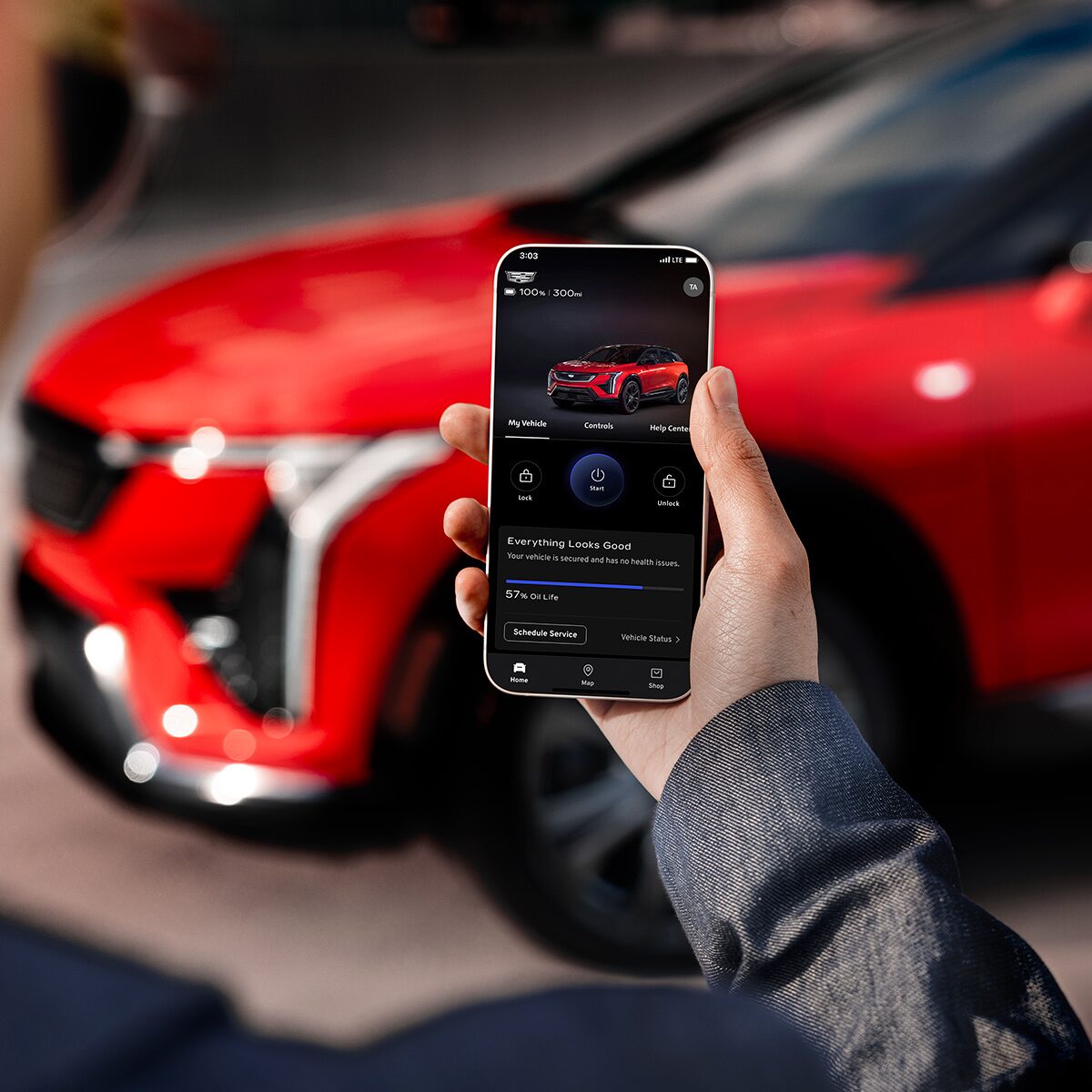 A Man Holding a Phone and Looking at the 2025 OPTIQ Range in the myCadillac Mobile App