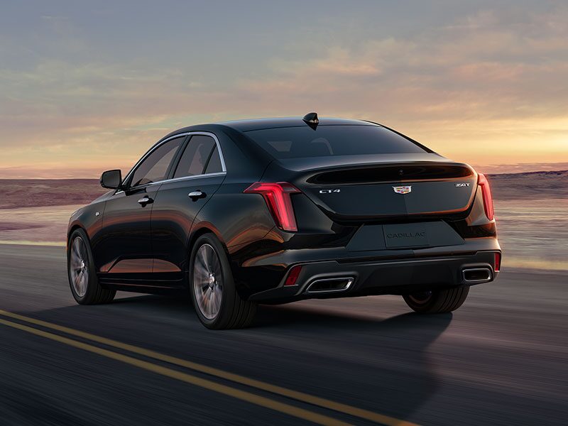 Three Quarters Rear View of a Black 2026 CT4 Driving Down a Desert Road