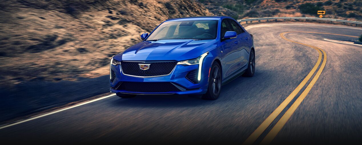 Front View of a Blue 2025 CT4 Driving Through a Curvy Mountain Road