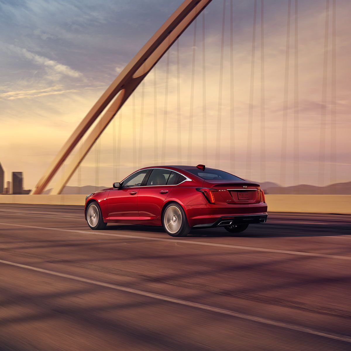 Side View of a Radiant Red Tintcoat 2025 Cadillac CT5 Driving on Bridge