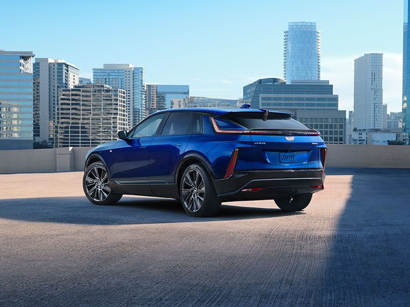 Three-Quarter Rear View of a Blue Cadillac LYRIQ Parked Overlooking the City Skyscrapers