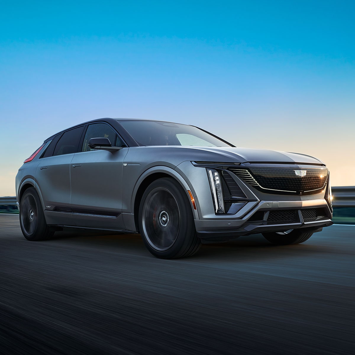 Three-quarter View of a Silver 2026 Cadilac LYRIQ-V Luxury Electric SUV Driving Down a Road