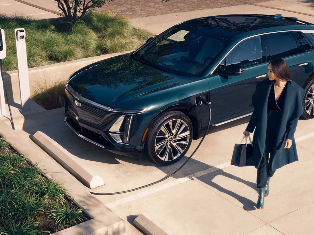 A Business Woman Walking Away From a Cadillac LYRIQ Charging at a Public Charger