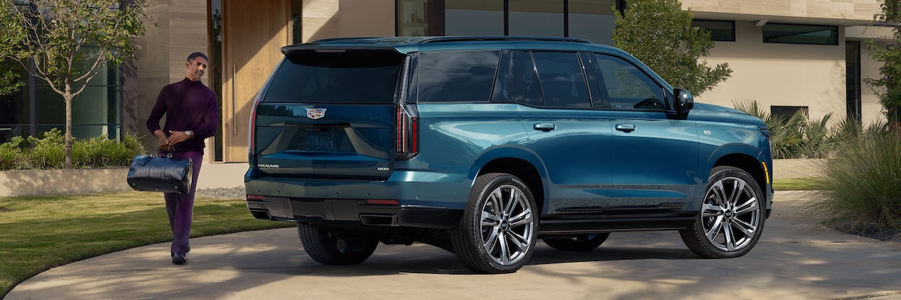 A Man with a Bag Walking Towards a Blue 2025 Escalade Parked in Front of a Home